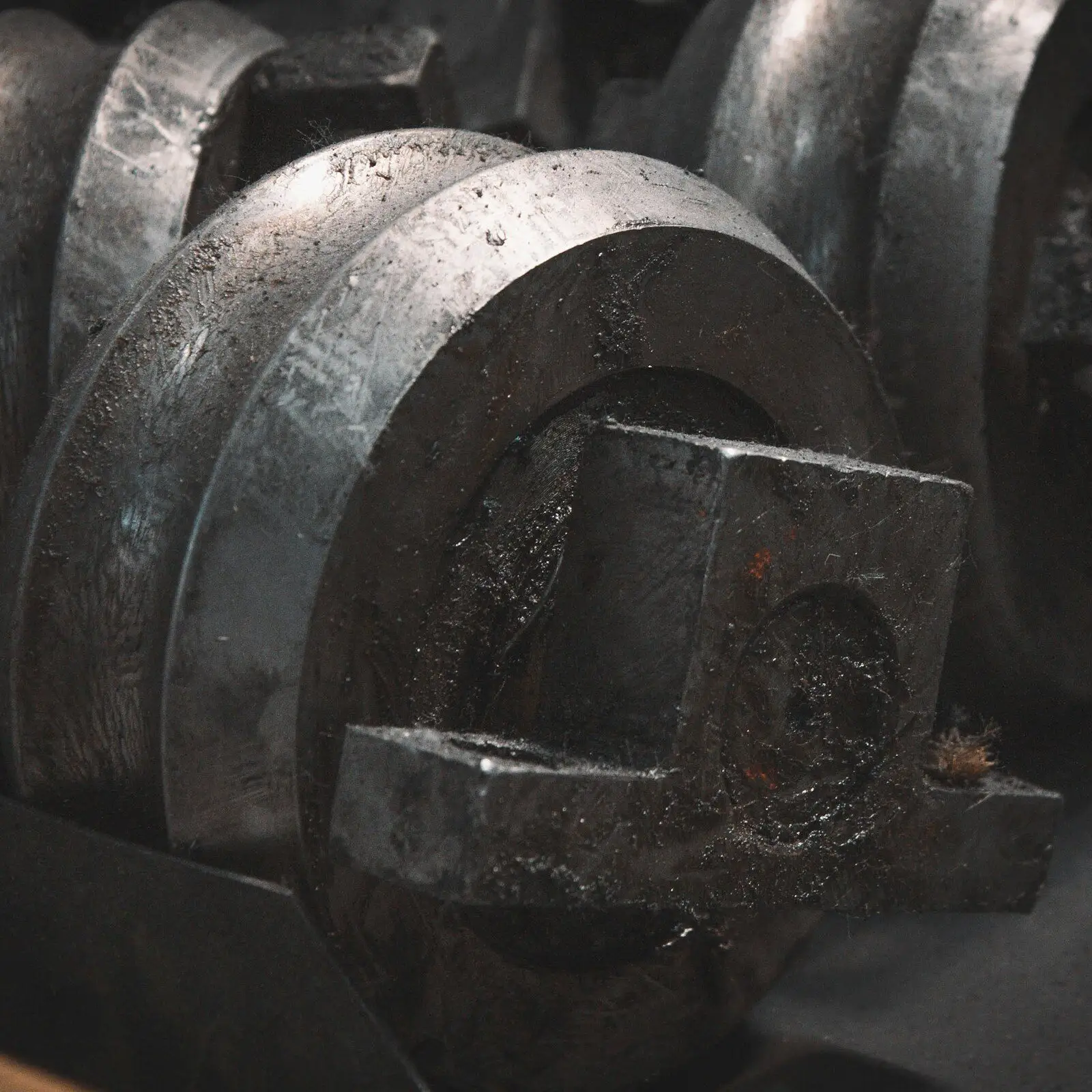 Heavy grooved forming rolls on a mill stand, worn and oiled from use.